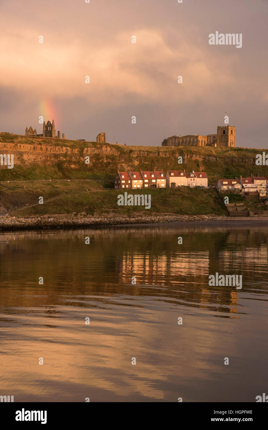 Blick auf die East Cliff (Häuser, Kirche St. Marien, Abtei Ruinen und Regenbogen) spiegelt sich in den Meer - Whitby, North Yorkshire, GB. Stockfoto