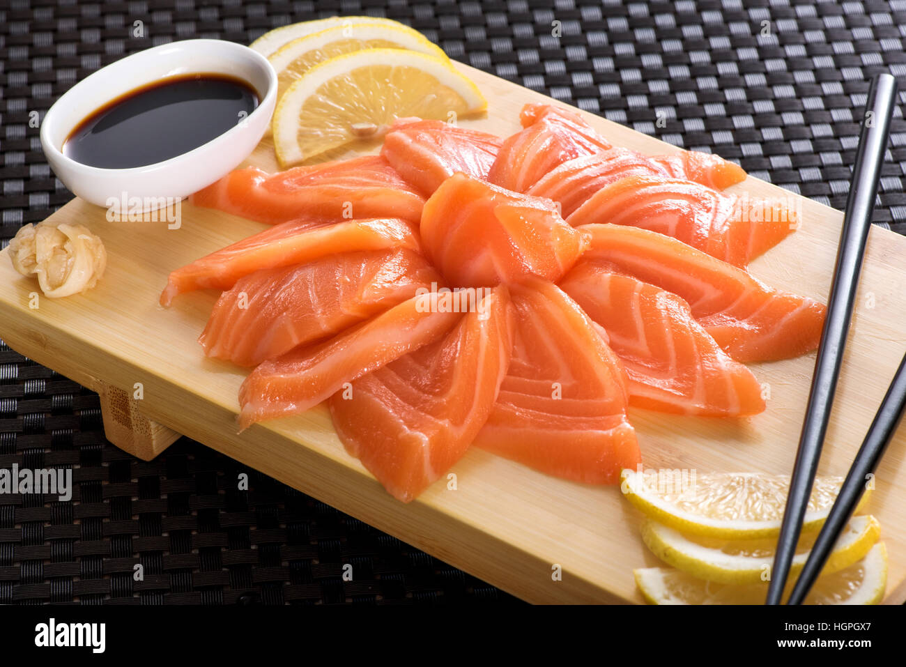 Sashimi Lachs mit Zitrone und Sojasoße serviert auf Holzbrett, japanische Küche Stockfoto