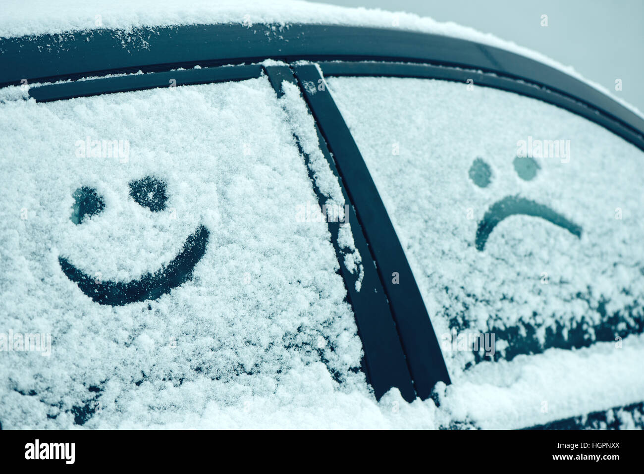 Glückliche und traurige Smiley Emoticon im Schnee auf Autoscheiben, Winter Saison Freude und Glück-Konzept Stockfoto