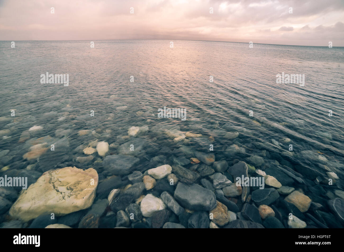 Friedliche Aussicht auf unberührte Flachmeer mit Steinen in den Boden und die leeren Horizont bei Sonnenuntergang Stockfoto