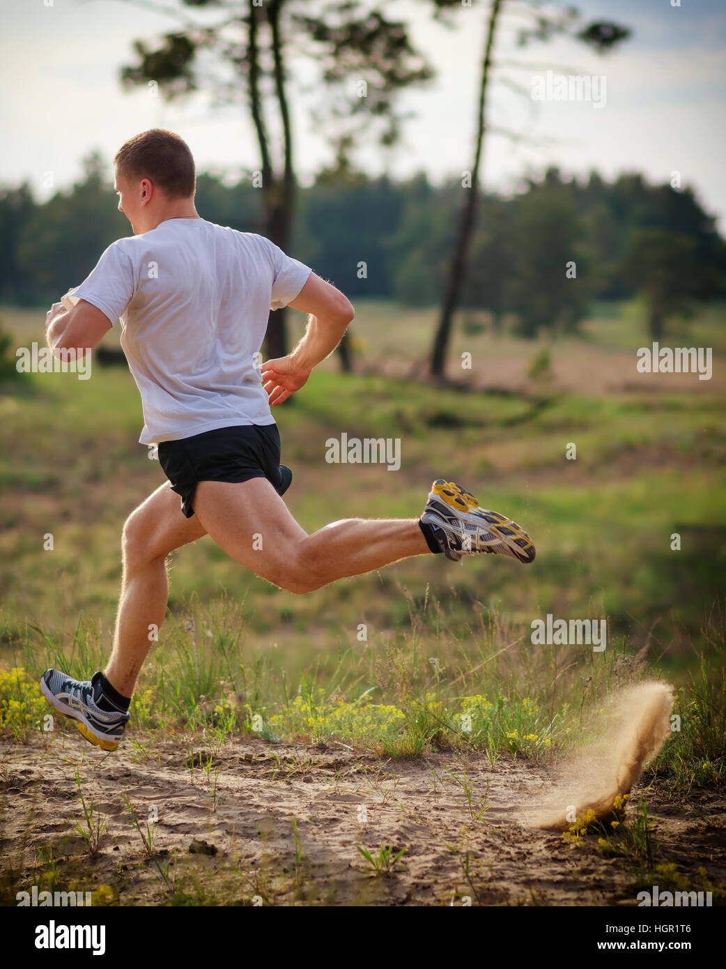 Junger Mann im freien laufen. Wegen der starken Anstoß unter den Fußsohlen des Sandes fliegt. Stockfoto