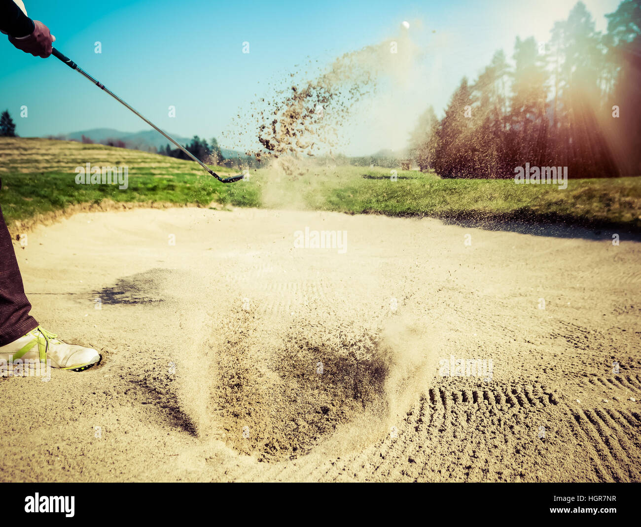 Golfer aus einem Sandfang schlagen. Der Golfplatz liegt auf dem Sand. Sand, so dass Spritzer. Sonne und Sonnenschein im Hintergrund Stockfoto