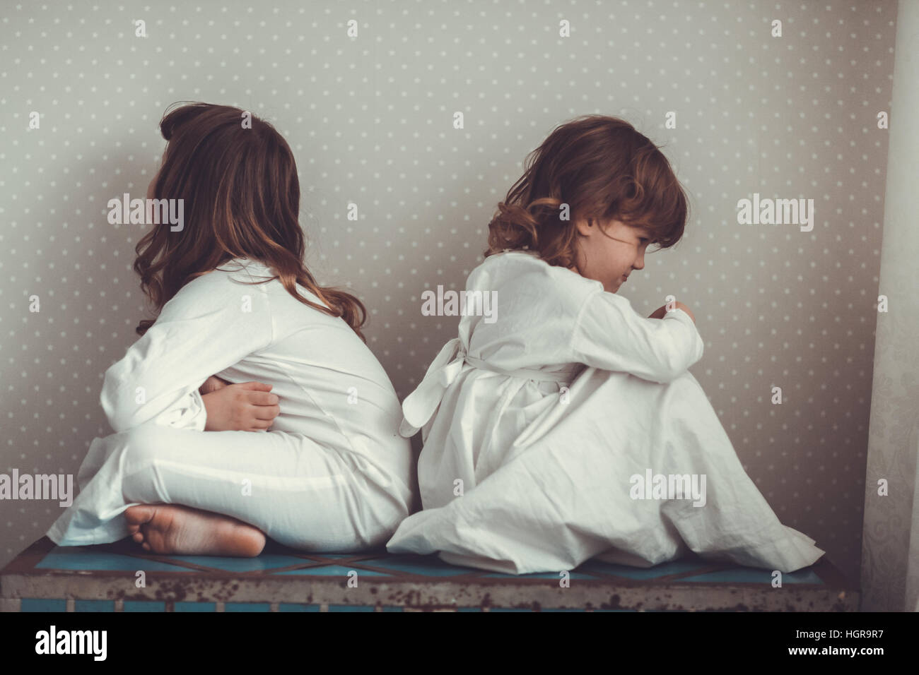 Geschwister-Schwestern in Nachthemden streiten, schwören und spielen Sie auf einem alten Stamm Stockfoto