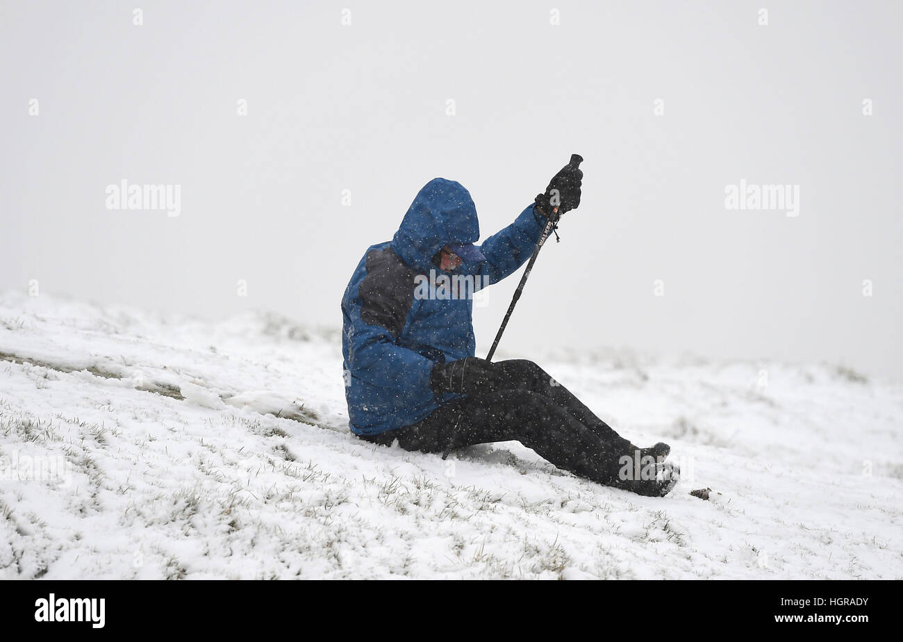 Terry Burrell aus Sheffield schlüpft auf einem verschneiten Mam Tor Hügel im Peak District, während die Schneesturm-Bedingungen sich einkehren werden und "einen echten Geschmack des Winters in ganz Großbritannien" bringen. Stockfoto