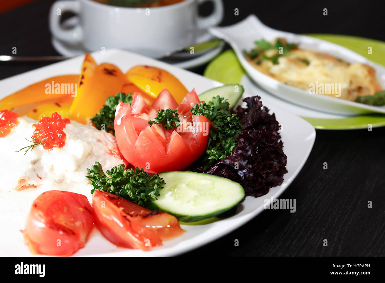 Fisch-Vorspeise mit Gemüse auf weißen Teller auf dunklen Holztisch Stockfoto
