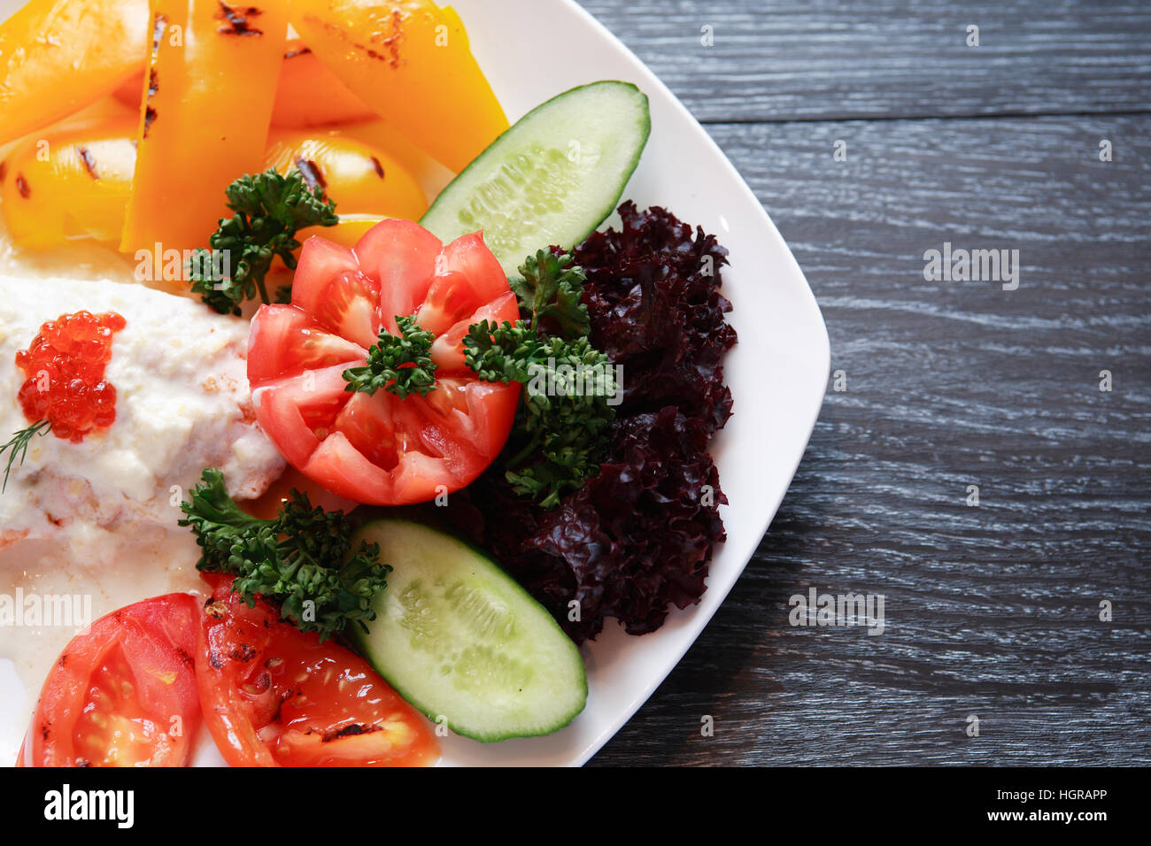 Fisch-Vorspeise mit Gemüse auf weißen Teller auf dunklen Holztisch Stockfoto