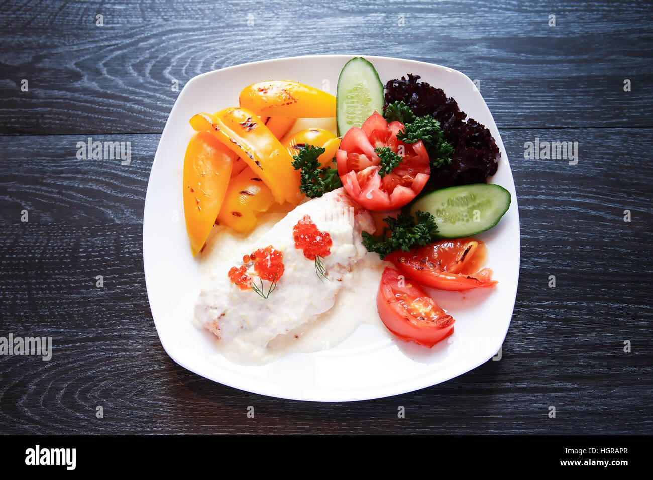 Fisch-Vorspeise mit Gemüse auf weißen Teller auf dunklen Holztisch Stockfoto