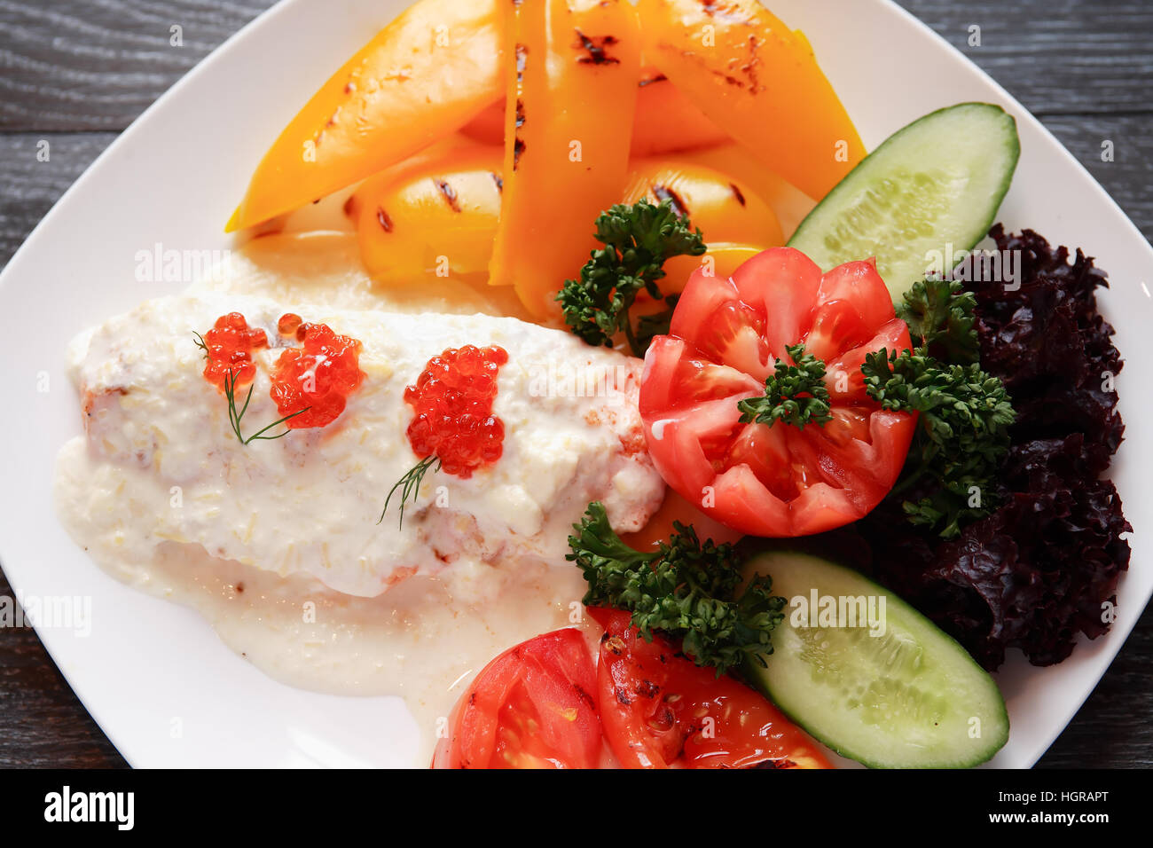 Fisch-Vorspeise mit Gemüse auf weißen Teller auf dunklen Holztisch Stockfoto