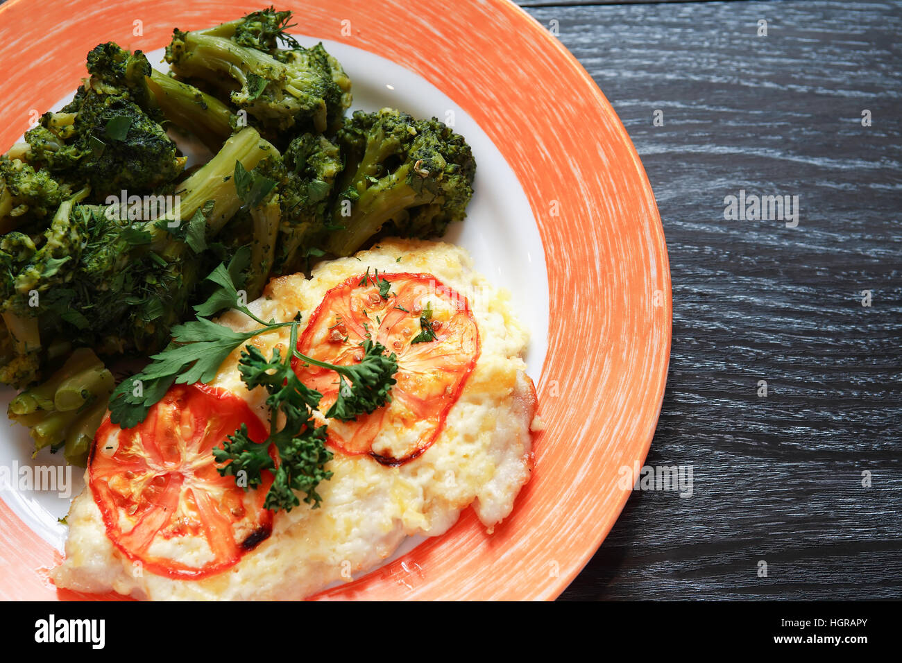 Teller mit gebratenen Fisch und Gemüse auf dunklen Holztisch Stockfoto