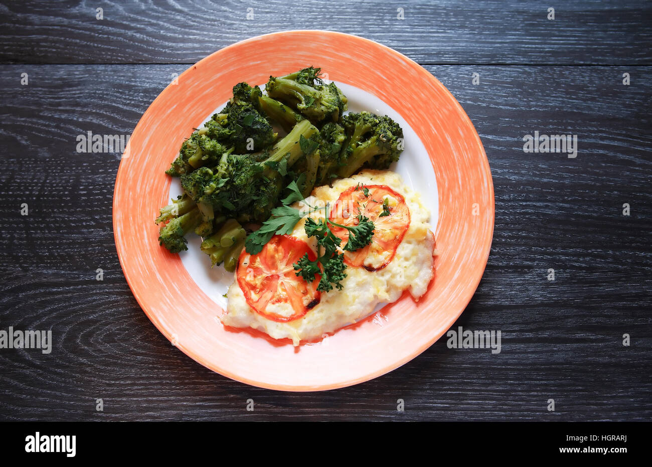 Teller mit gebratenen Fisch und Gemüse auf dunklen Holztisch Stockfoto