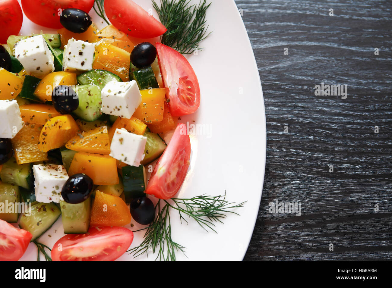 Aperitif zum Abendessen. Platte mit griechischer Salat auf dunklen Holztisch Stockfoto