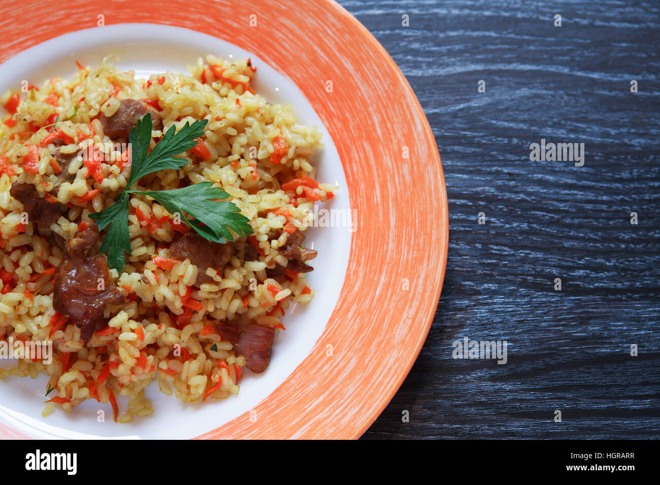 Platte mit Pilaw auf Platte Closeup auf dunklen Holztisch mit freiem Speicherplatz Stockfoto