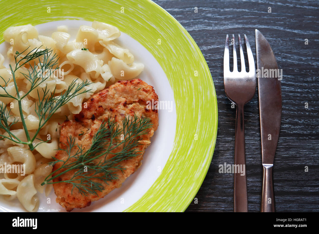 Platte mit Schnitzel und Pasta auf dunklen Holztisch Stockfoto