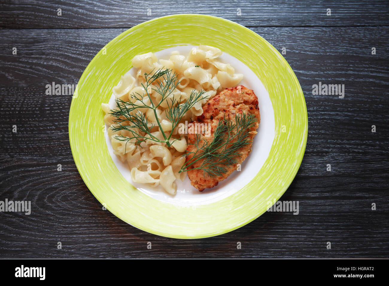 Platte mit Schnitzel und Pasta auf dunklen Holztisch Stockfoto