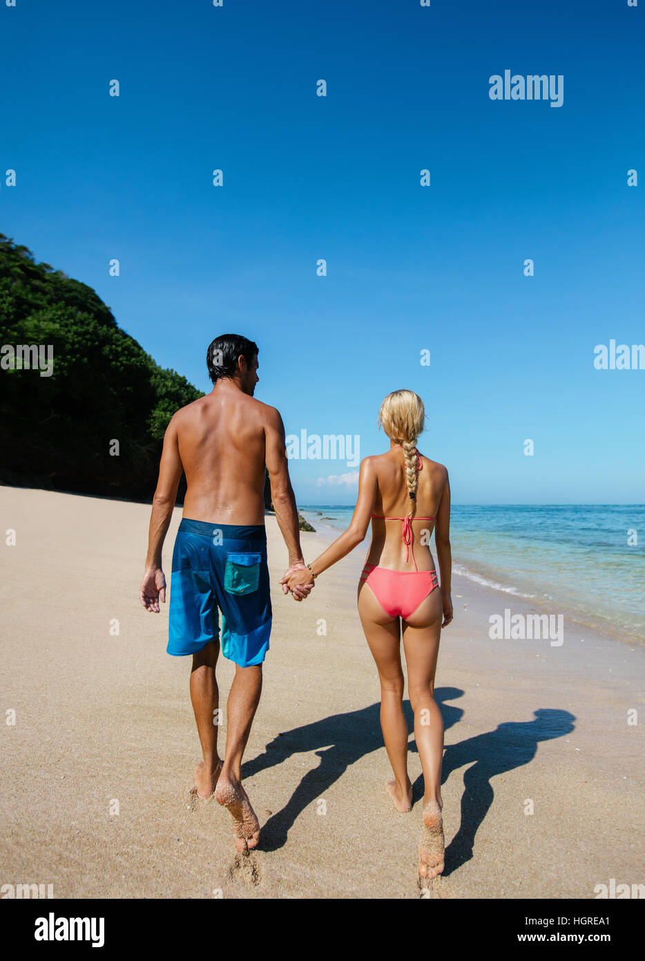 Rückansicht Schuss junges Paar Hand in Hand am Strand entlang spazieren. Paar in der Liebe in den Sommerferien am tropischen Strand. Stockfoto