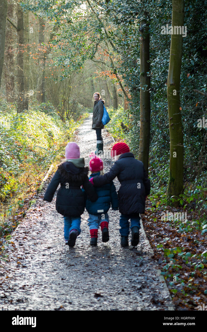 Mutter & 3 Kinder drei Kinder Töchter gehen / laufen auf schlammigen Weg / im Schlamm auf Gehweg Weg Fuß Weg Fußweg Esher UK Stockfoto