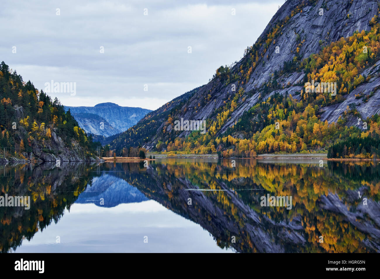 Bergseite mit Baum Vegetation Spiegelung in völlig ruhiger See in einem See in Norwegen Stockfoto