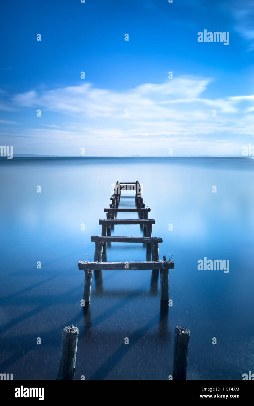 Hölzerne Pier oder Steg bleibt auf einen blauen See Sonnenuntergang. Lange Belichtung Fotografie Stockfoto