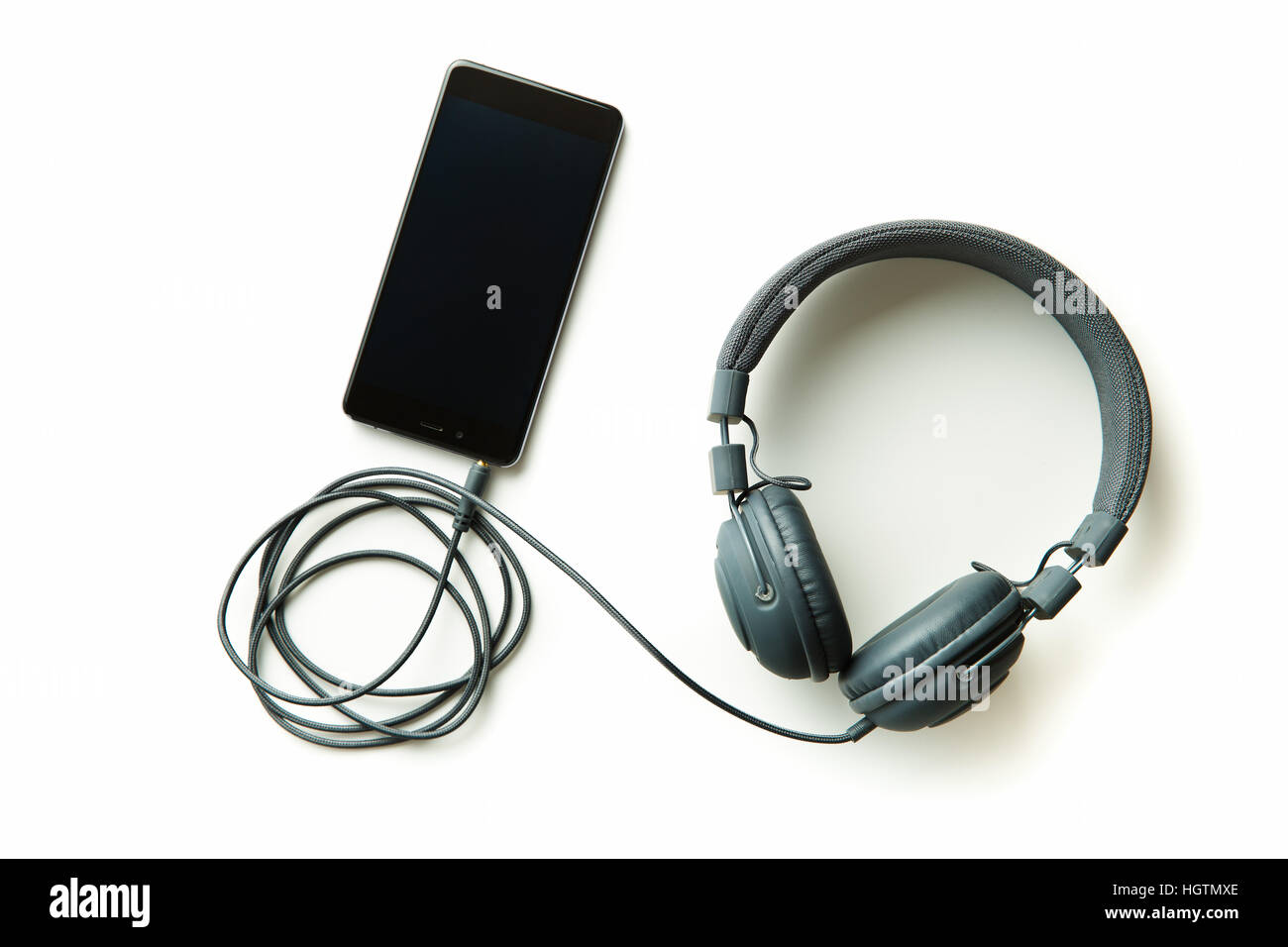 Graue Vintage Kopfhörer und Handy isoliert auf weißem Hintergrund. Stockfoto