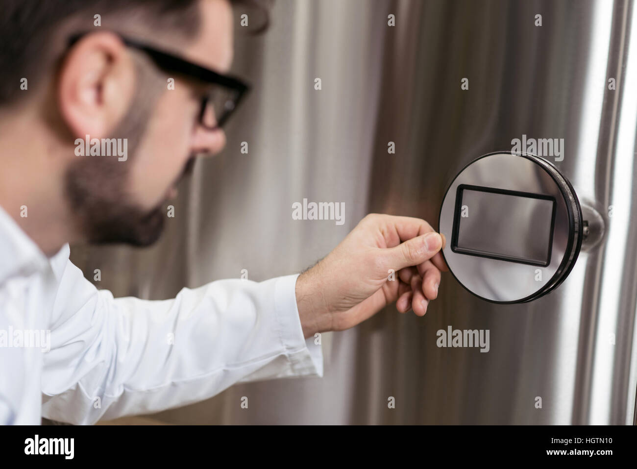 Ernster Mann Drücken einer Taste auf Brauen Mechanismus Stockfoto