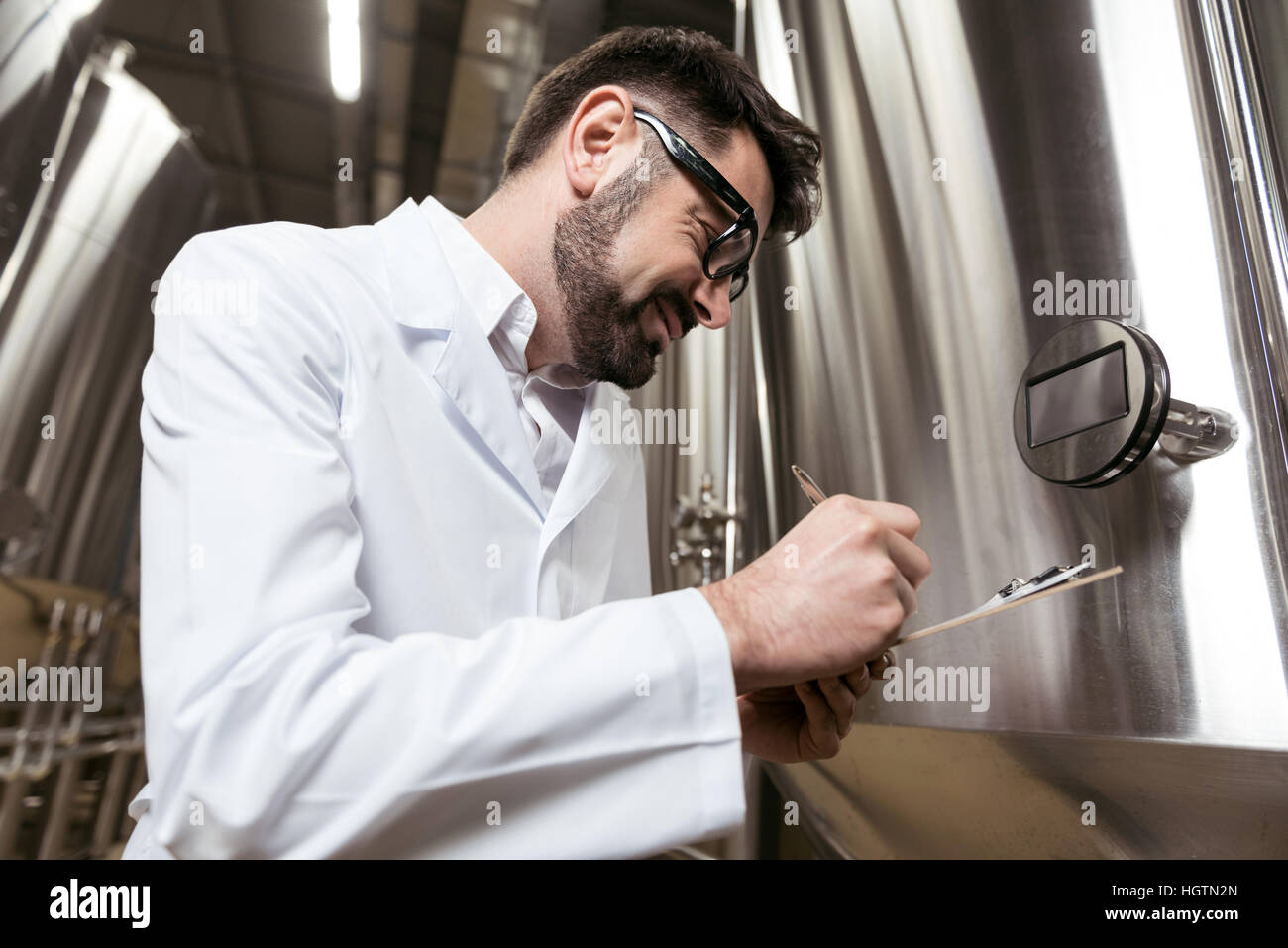 Lächelnder Mann Notizen bei Bierfabrik Stockfoto