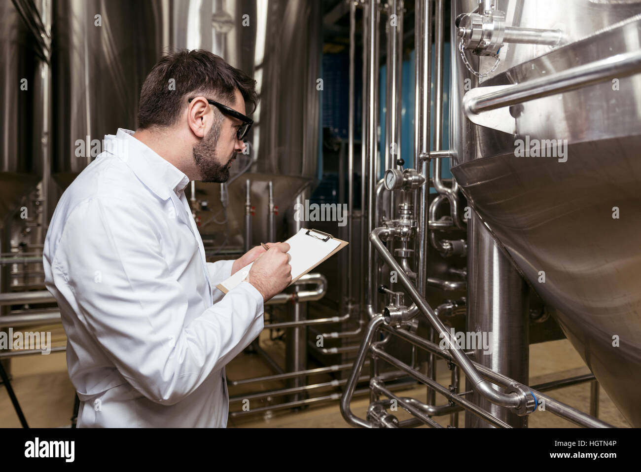 Konzentrierende Mann Notizen bei Bierfabrik Stockfoto