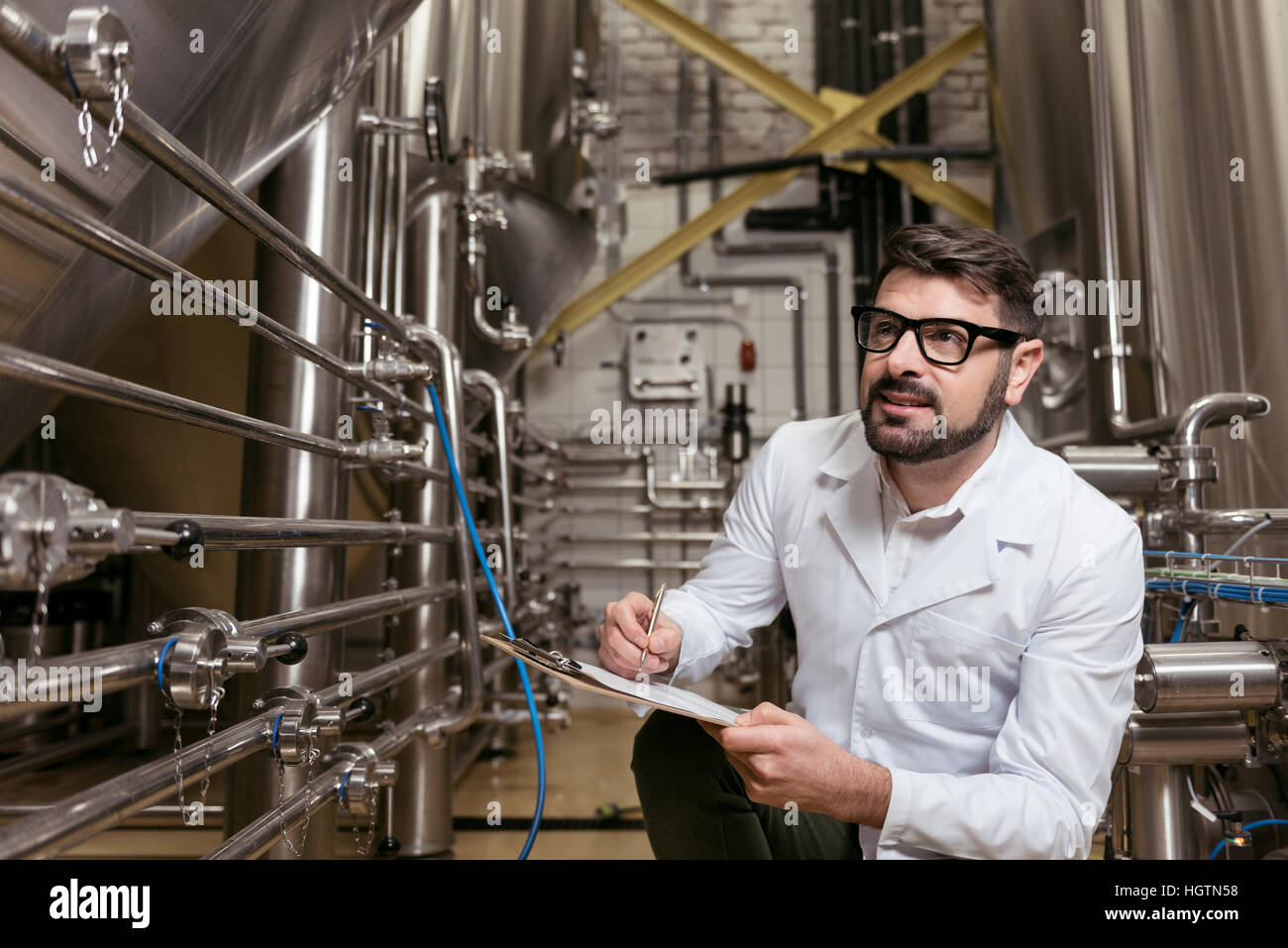 Amüsiert Mann sitzt am Bierfabrik Stockfoto