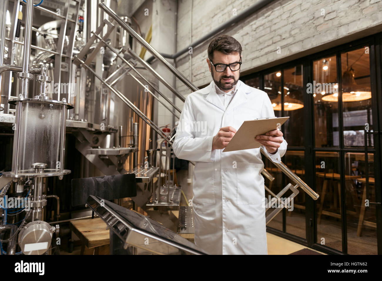 Konzentrierte Mann steht am Bierfabrik Stockfoto