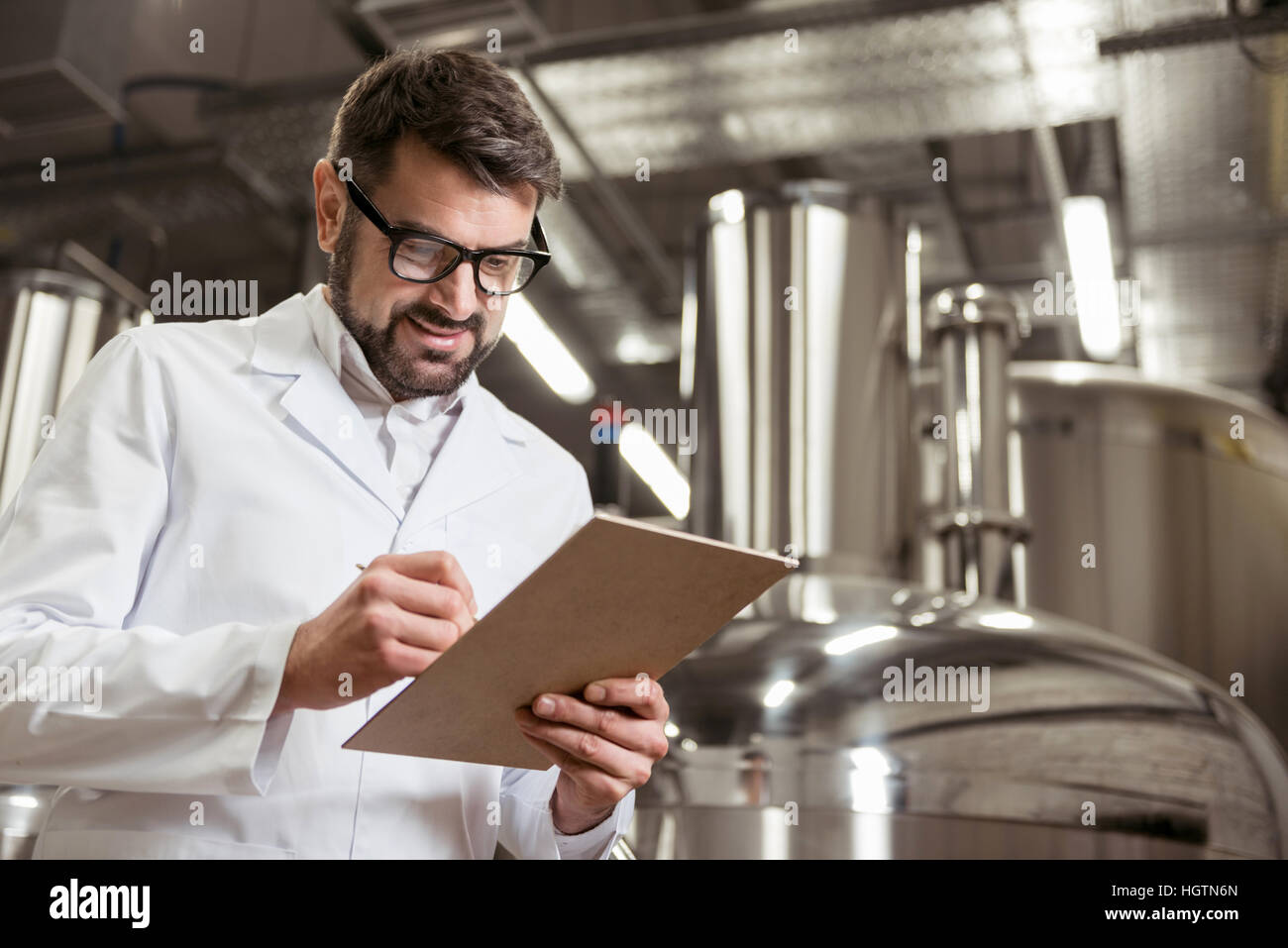 Lächelnder Mann Notizen bei Bierfabrik Stockfoto