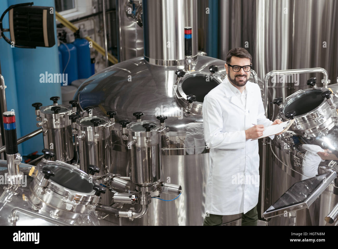 Lächelnder Mann Kontrollmechanismen bei Bierfabrik Stockfoto