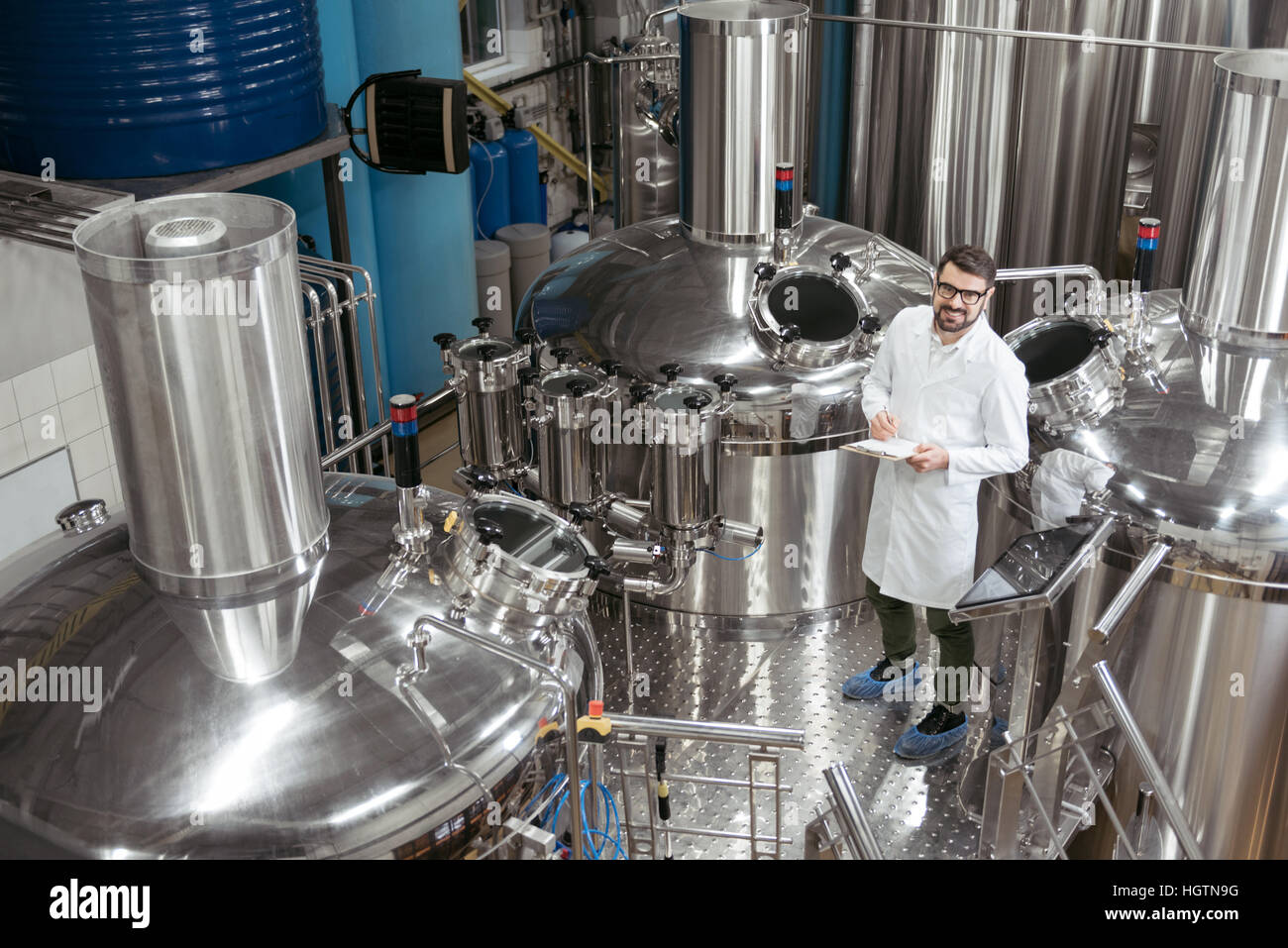 Lächelnder Mann stehend in Maschinen bei Bierfabrik Stockfoto