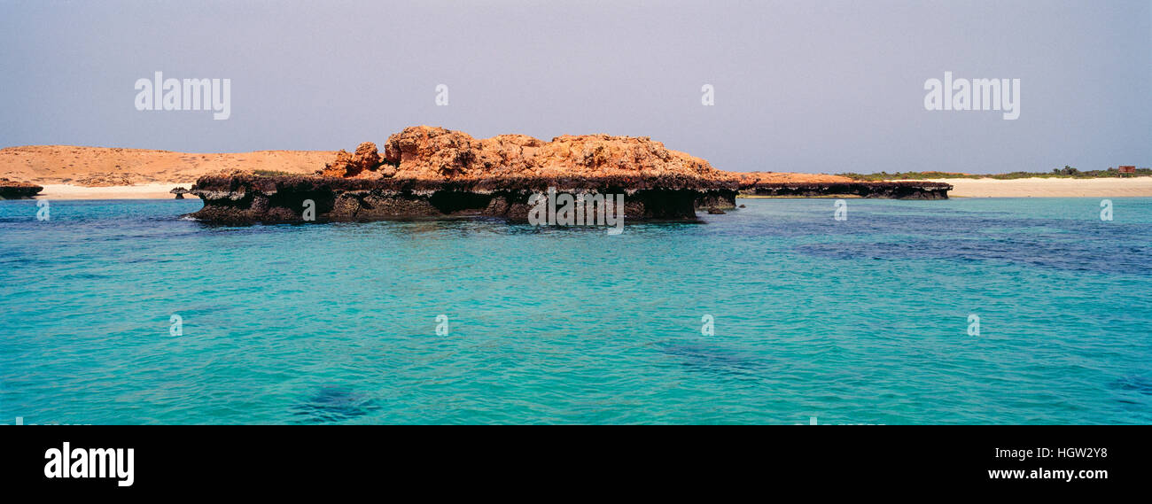 Klare, türkisfarbene See umgeben von einer kargen rote Wüste Sandinsel. Stockfoto