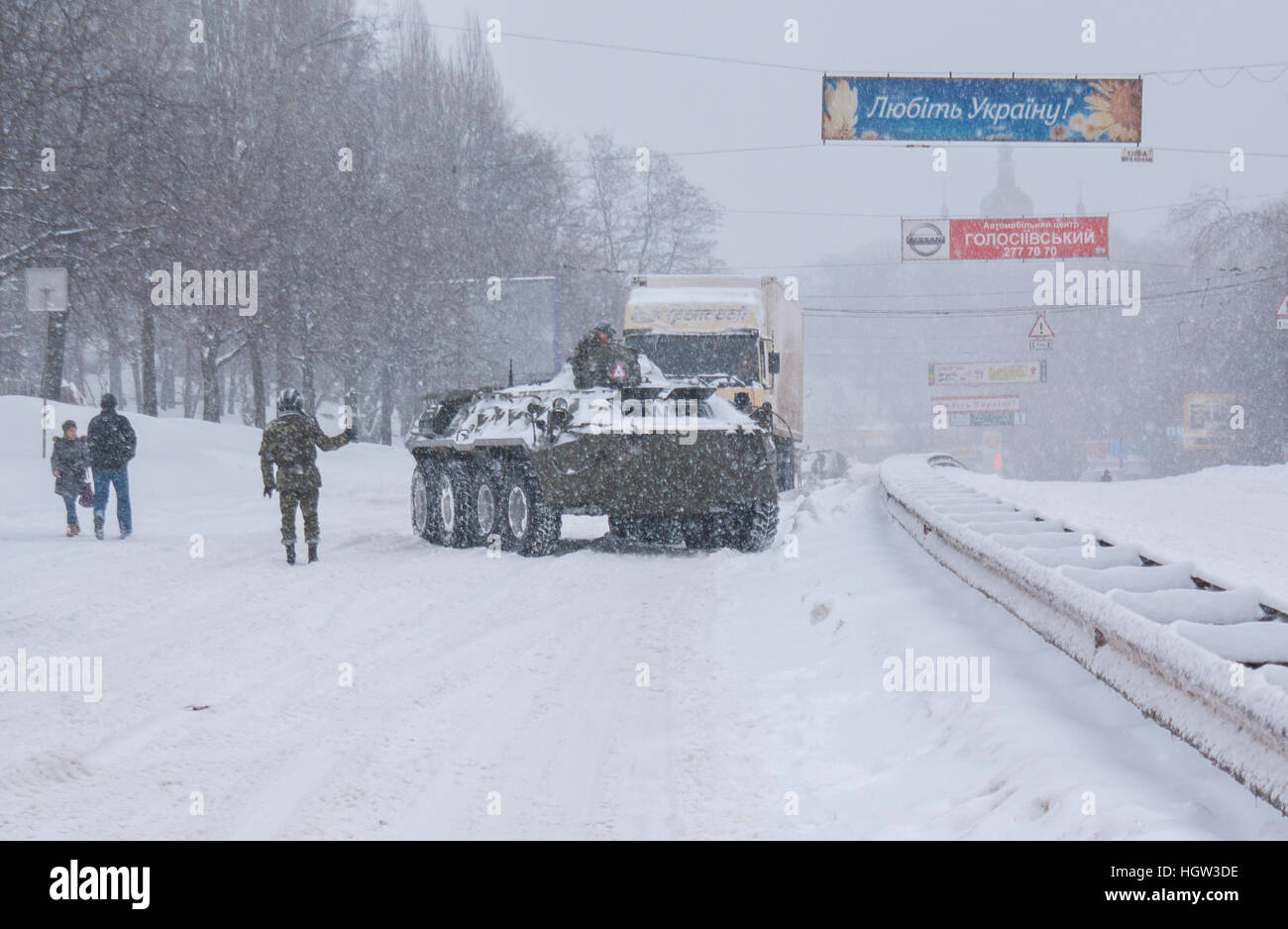der gepanzerte Truppentransporter der Katastrophenschutzministerium hilft die Lastwagen, verschneiten Aufstieg auf der Straße, Kiew, Ukraine zu überwinden Stockfoto
