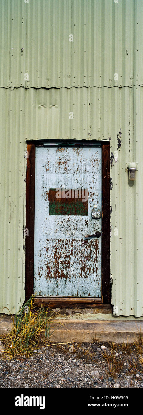 Eine gewellte Zinn Wand und Stahltür in einer alten Fabrik. Stockfoto