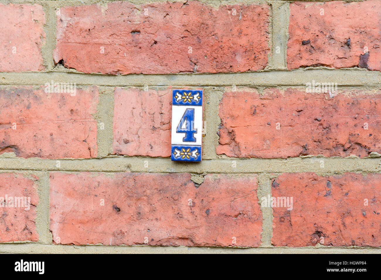Hausnummer 4 Zeichen - kleine keramische Fliesen auf roten Backsteinmauer Stockfoto