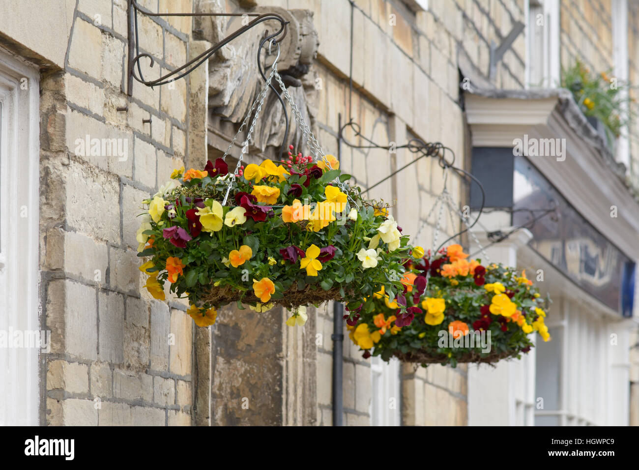 Hängenden Körben voller Frühlingsblumen vor Haus Stockfoto
