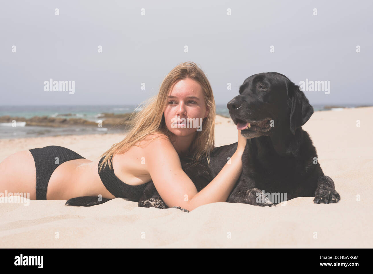 Blonde Teenager mit ihr Haustier Labrador am Strand. Stockfoto