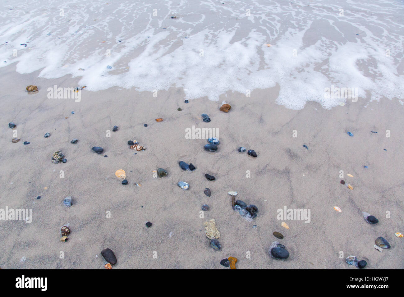 Welle an einem Strand mit bunten Steinen in Helgoland Stockfoto
