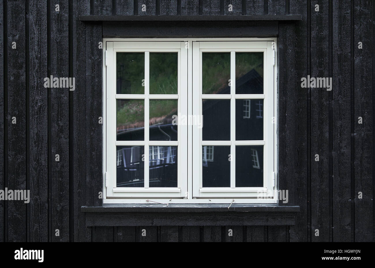 Kolonialstil Casement-Fenster von weißem lackiertem Holz in einer schwarzen Nut Plank Fassade Stockfoto