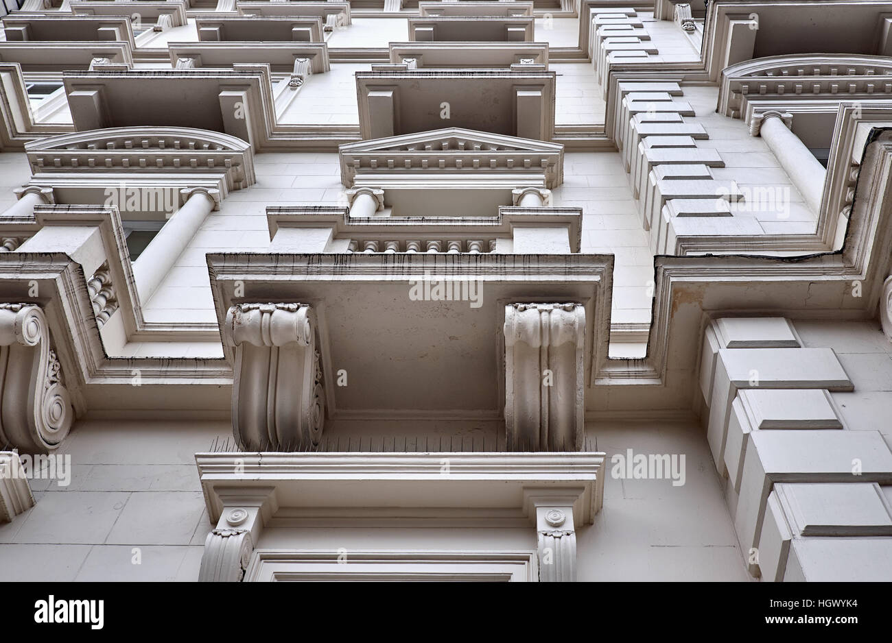 Abschnitte einer verputzten Fassade mit aufwendigen Dekorationen rund um die Fenster und Balkone eines Gebäudes in London City Stockfoto