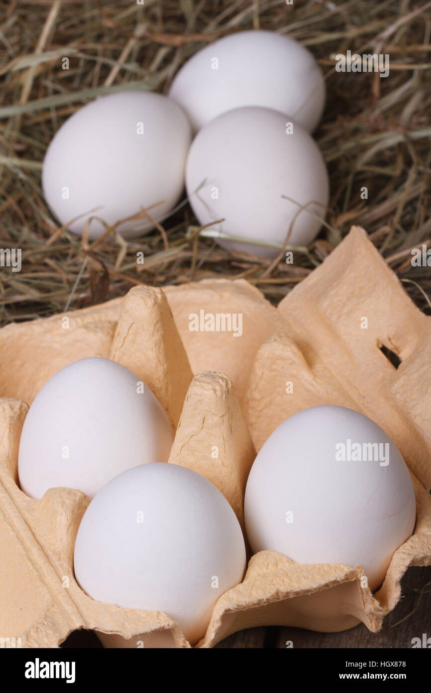 weiße Hühnereier in ein Fach und eine Heu-Nahaufnahme. vertikale Stockfoto