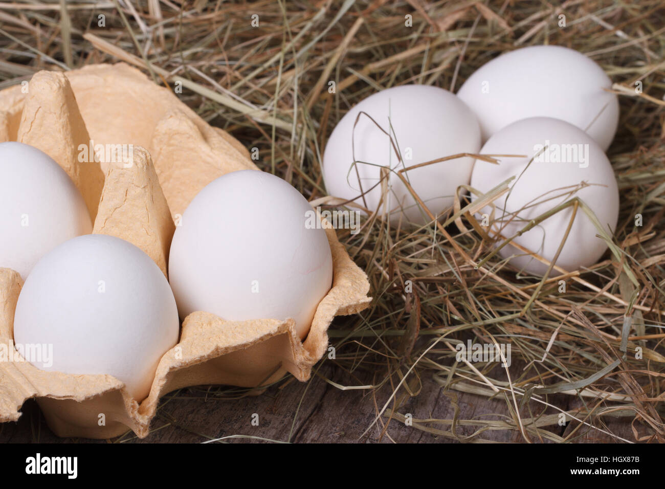 Sehr frische weiße Hühnereier in einem Fach und Heu Nahaufnahme. horizontale Stockfoto