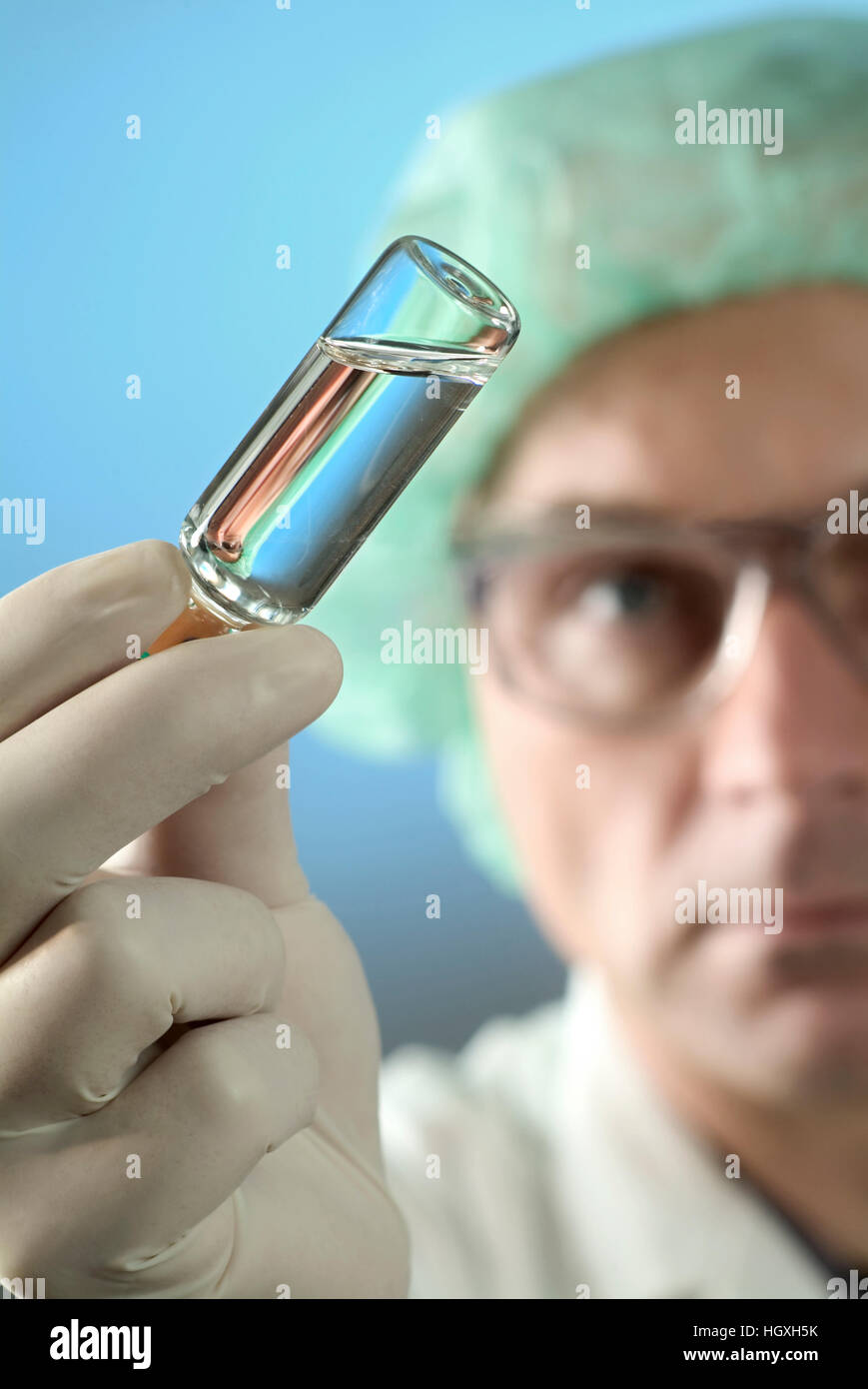 Wissenschaftler hält eine kleine Flasche mit klarer Flüssigkeit zu überprüfen. Stockfoto