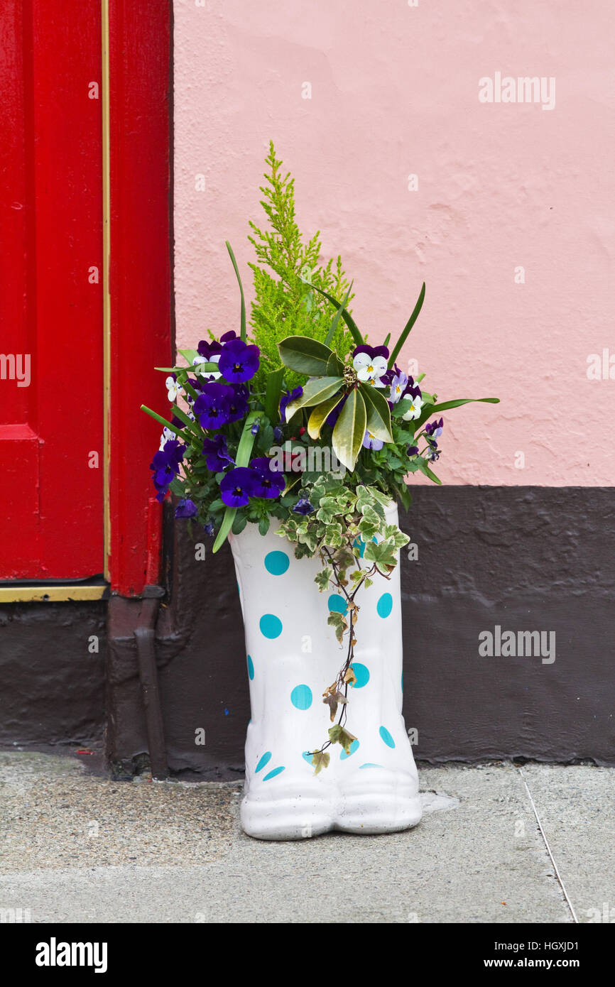 Farbenfrohe Gummistiefel gefüllt mit Blumen schmücken Häuser, Tore und Türen von der irischen Küste Dorf Courtmacsherry im County Cork. Stockfoto