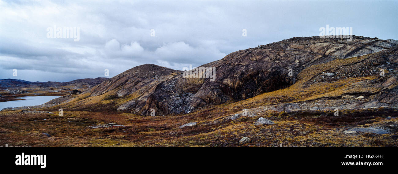 Aufschlüsse über exponierte unfruchtbaren Felsen entstehen durch die Tundra umgibt ein Bergsee. Stockfoto