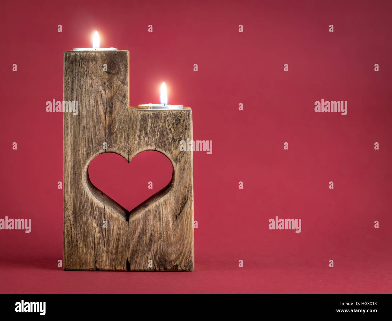 Beleuchteten romantischen hölzernen Kerzenständer mit ausgeschnittenen Herzen auf rotem Grund Stockfoto