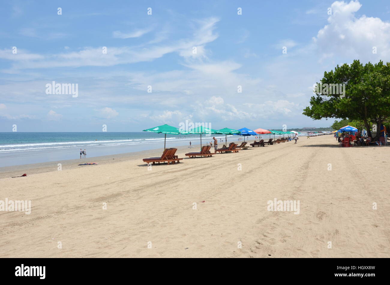 Liegestühle und Sonnenschirme an einem bewölkten sonnigen Tag am Strand von Kuta, Bali, Indonesien Stockfoto