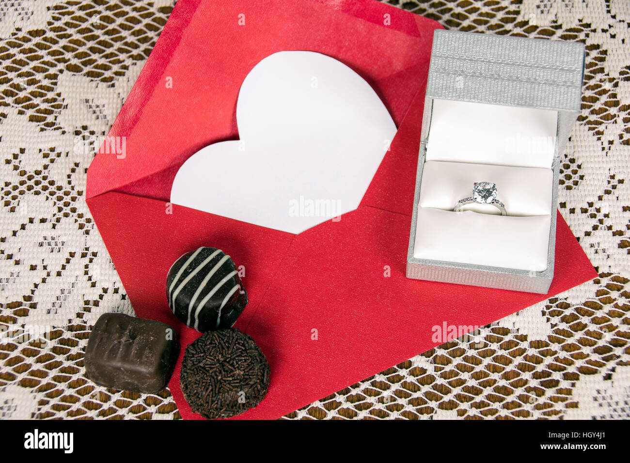 Schokolade Süßigkeiten-Diamant-Ring auf roten Umschlag mit weißen Herzen Stockfoto