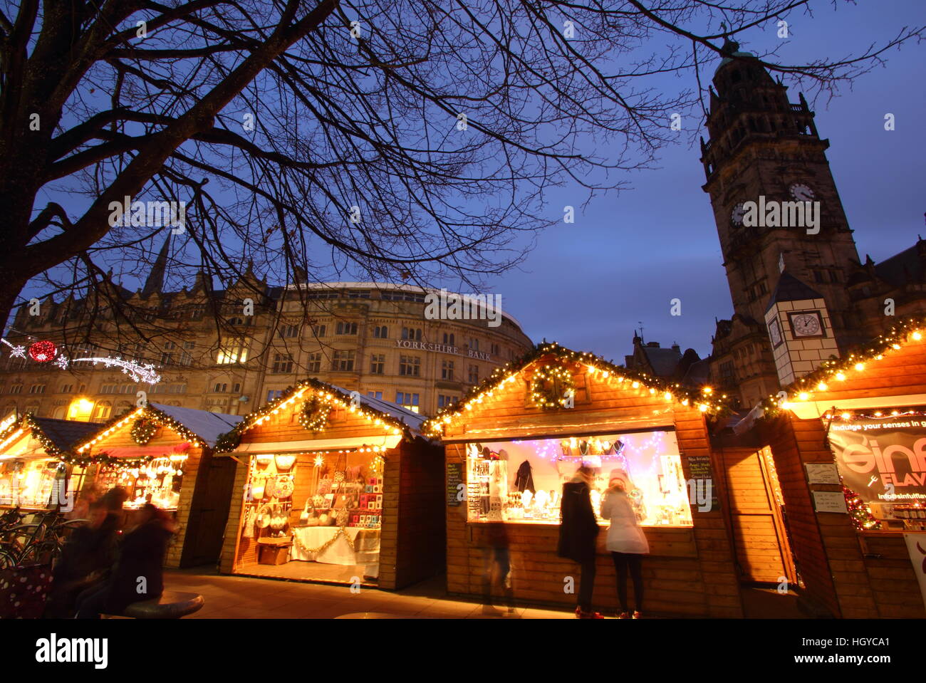Festliche Shopper durchsuchen waren in niedlichen Holzhütten auf dem Weihnachtsmarkt am Fargate Sheffield Stadtzentrum Yorkshire, England Stockfoto