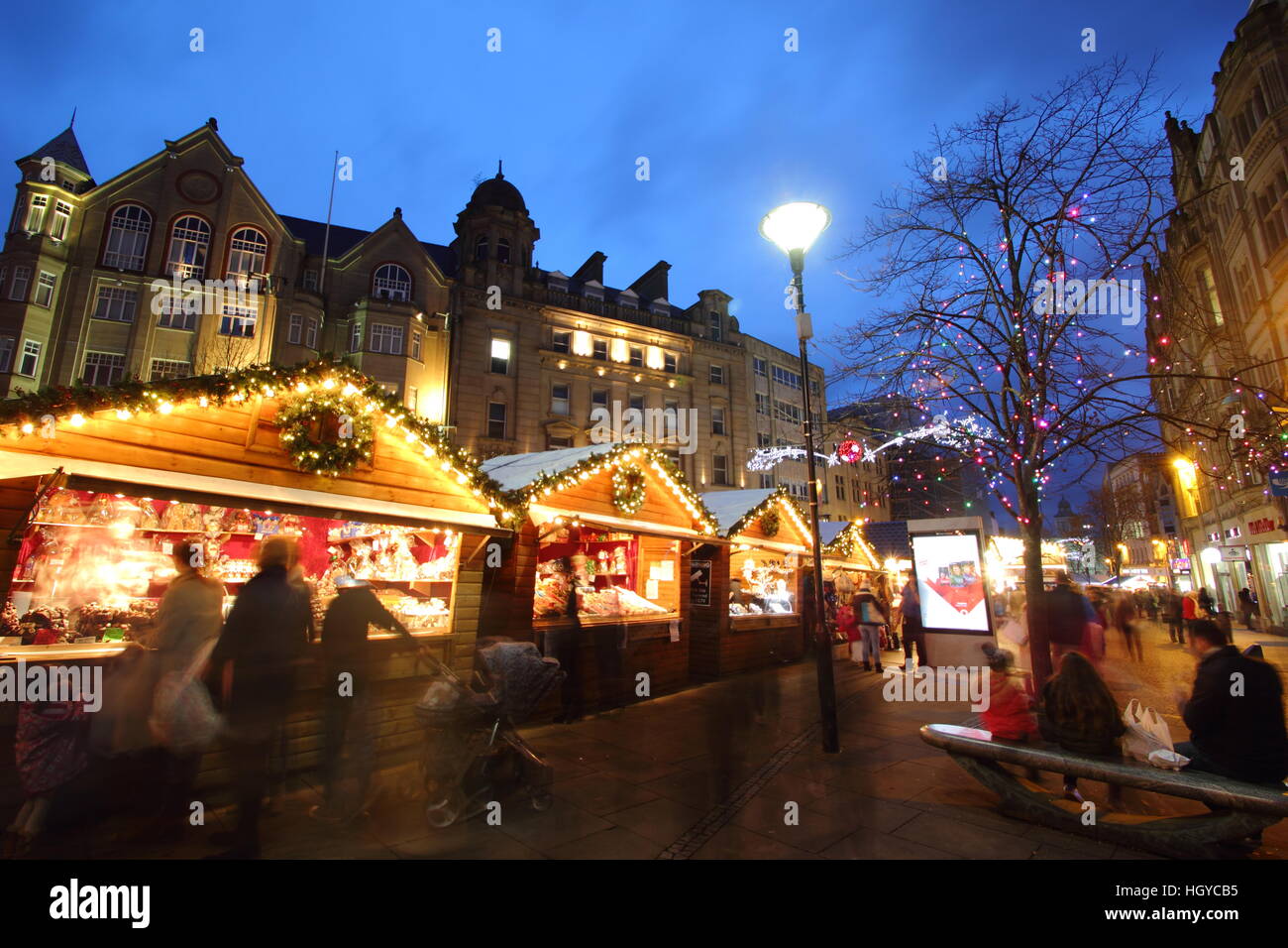 Festliche Shopper durchsuchen waren in niedlichen Holzhütten auf dem Weihnachtsmarkt am Fargate Sheffield Stadtzentrum Yorkshire, England Stockfoto